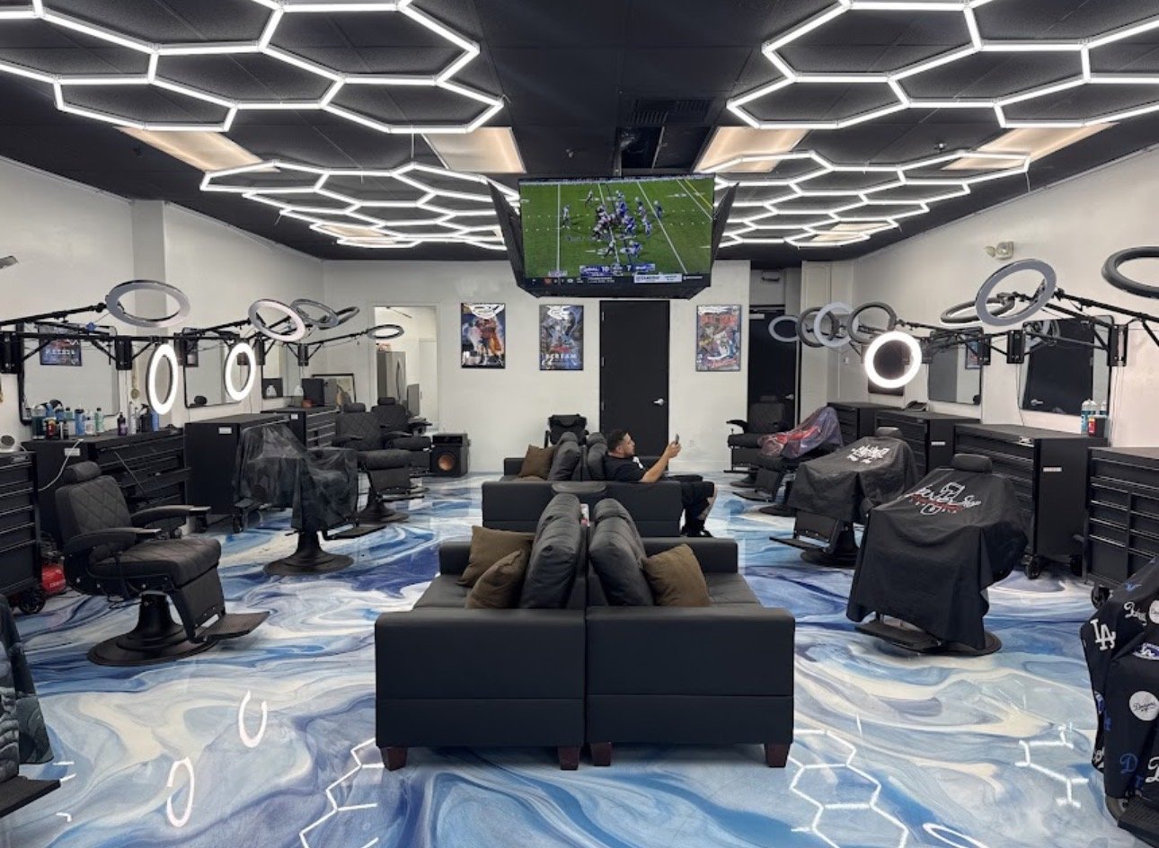 Inside SoCal Barber Studio — hex ceiling, marble floor, sixteen chairs